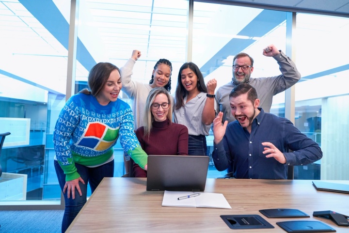 Customer services representatives celebrating at a laptop after delivering some fantastic customer experiences.